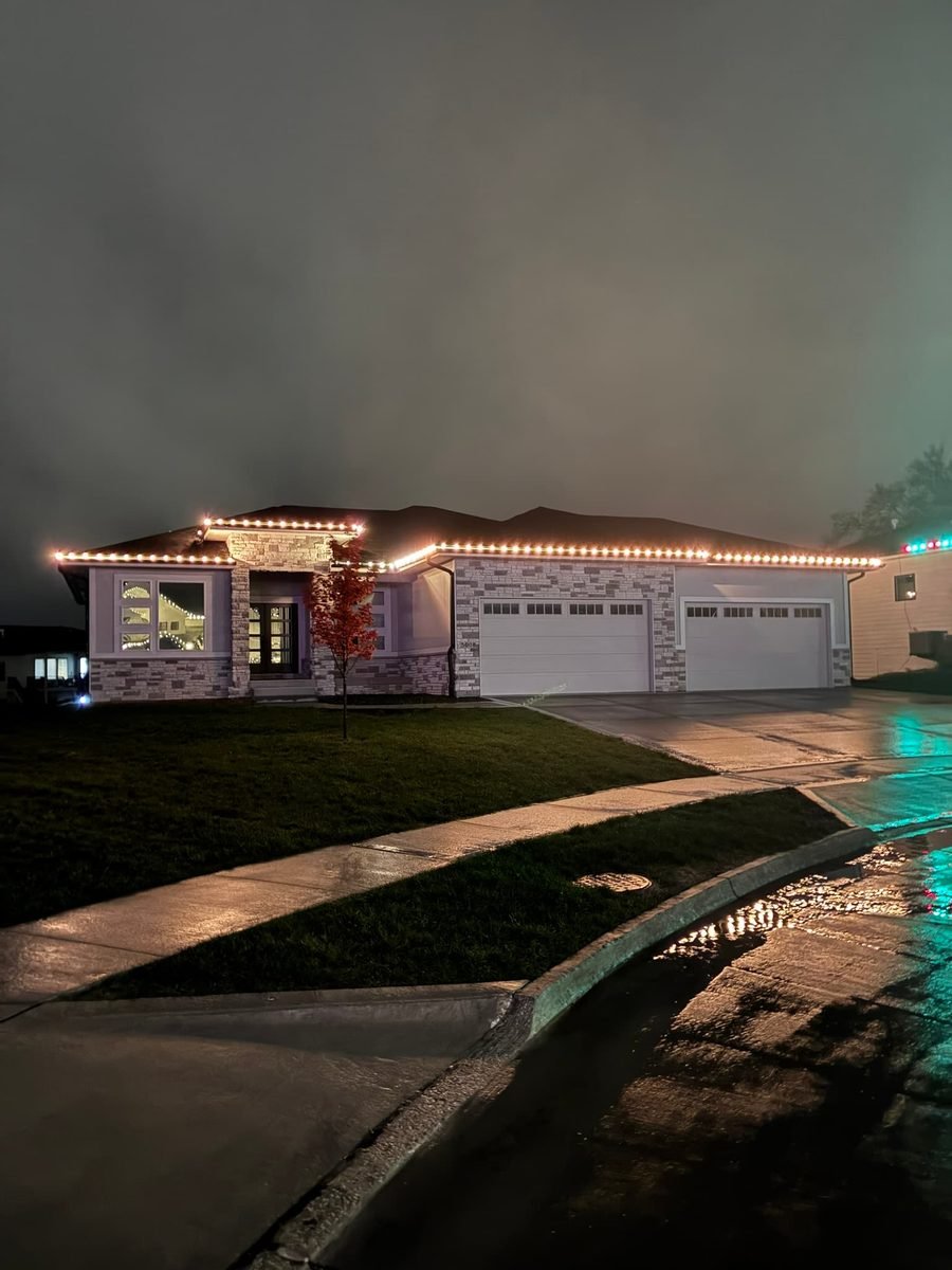 Warm white C9 bulbs running the full gutter line and front peak of a two story house at dusk