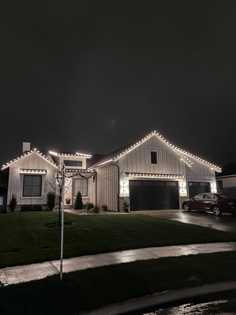 Evenly spaced warm white C9 bulbs following the front gutter line of a home at night