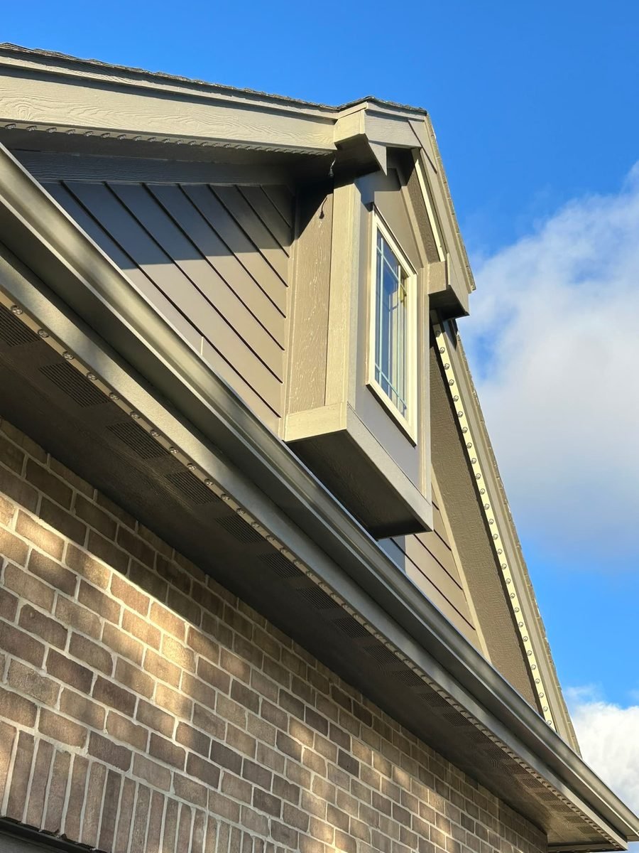 Permanent roofline track lighting fitted under the shingle line of a house in daylight