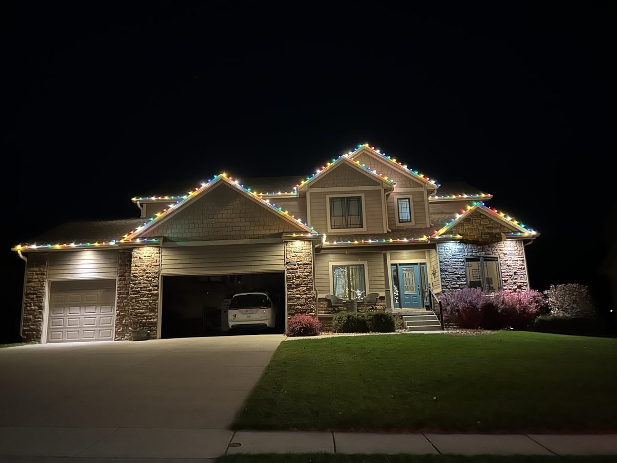 Warm white roofline lighting tracing every peak and eave of a large two story house