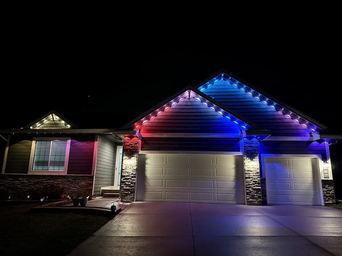 Permanent roofline lighting channel mounted under the eaves of a house, lit warm white