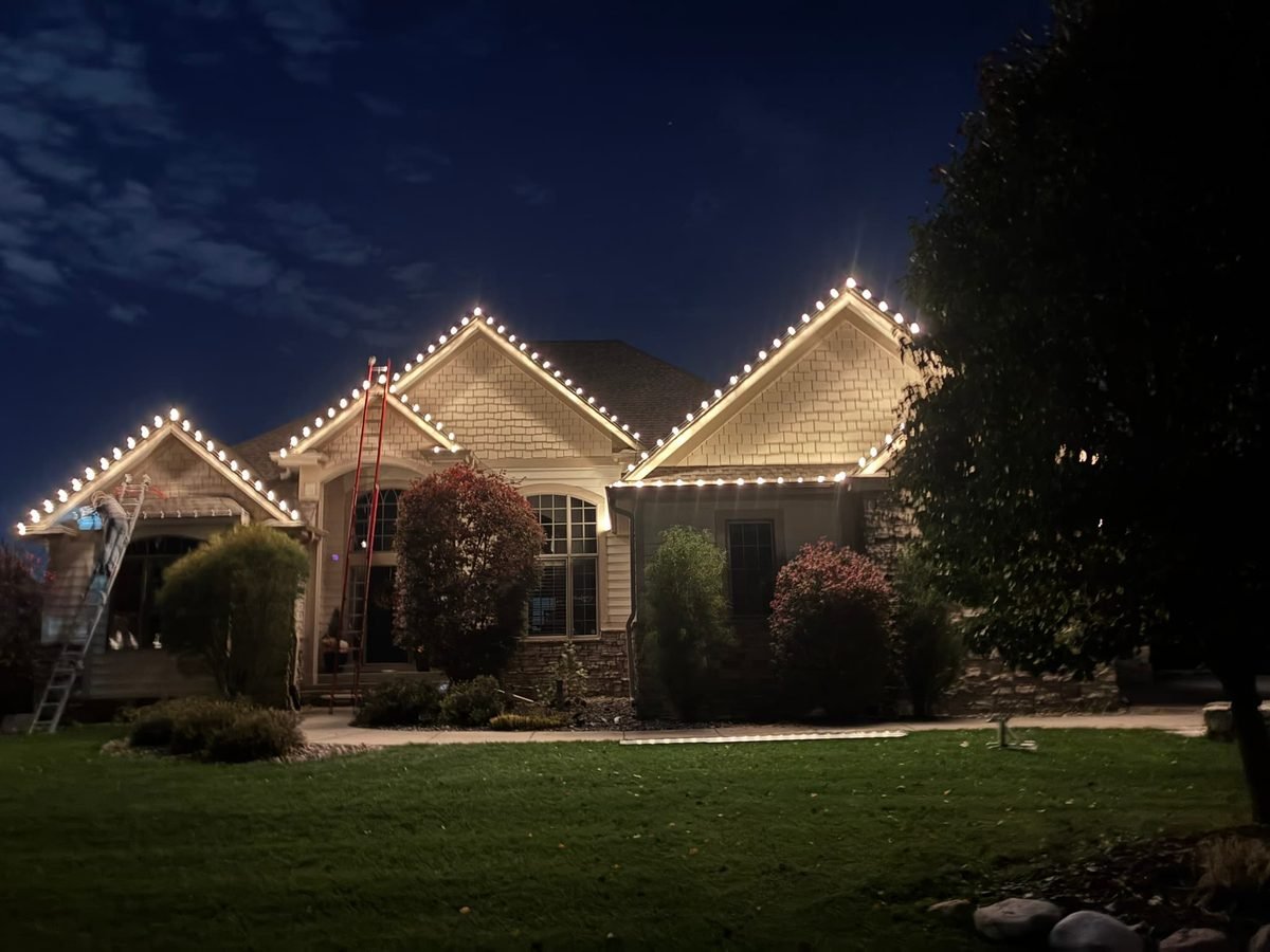 Warm white C9 roofline lighting on an Urbandale home at night, following every eave and peak