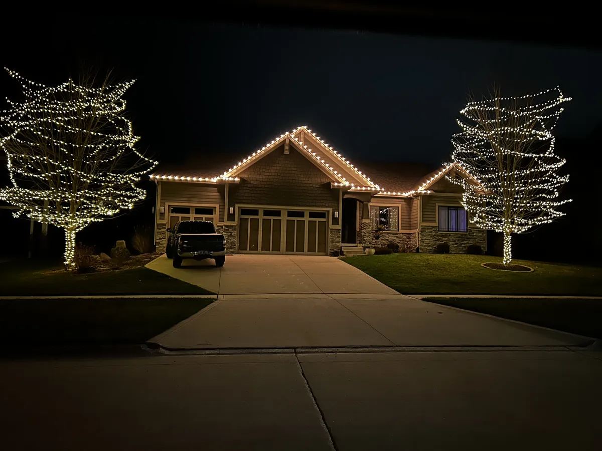 Warm white C9 bulbs running an even line along a low single story gutter and front peak at dusk